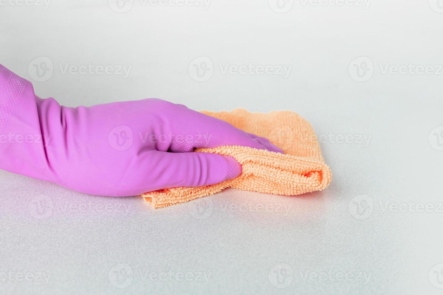 a hand in a pink glove wipes the surface with yellow microfiber. High quality photo