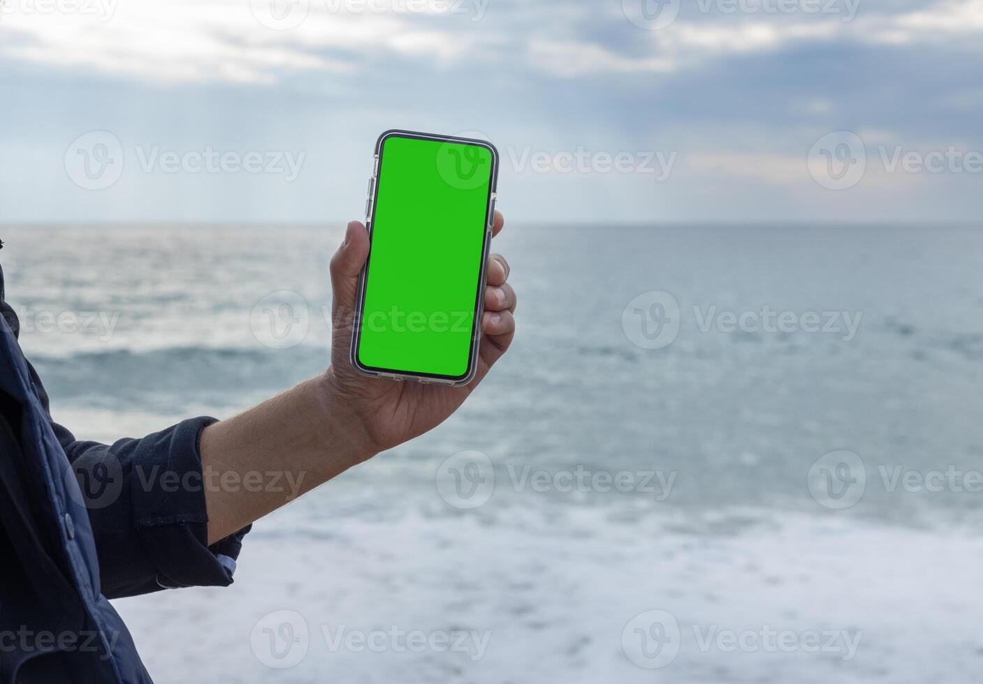 hands of a man pointing his finger at a mobile phone with a blank green screen. High quality photo