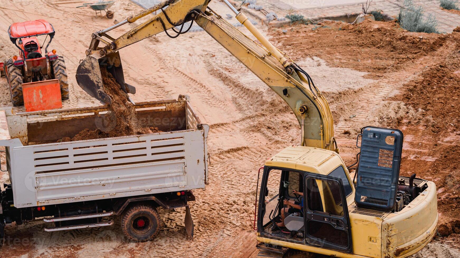 Backhoe excavating ground. Construction site, a powerful backhoe loader maneuvers adeptly, excavating the ground into a truck, showcasing the efficiency of heavy machinery at work. photo