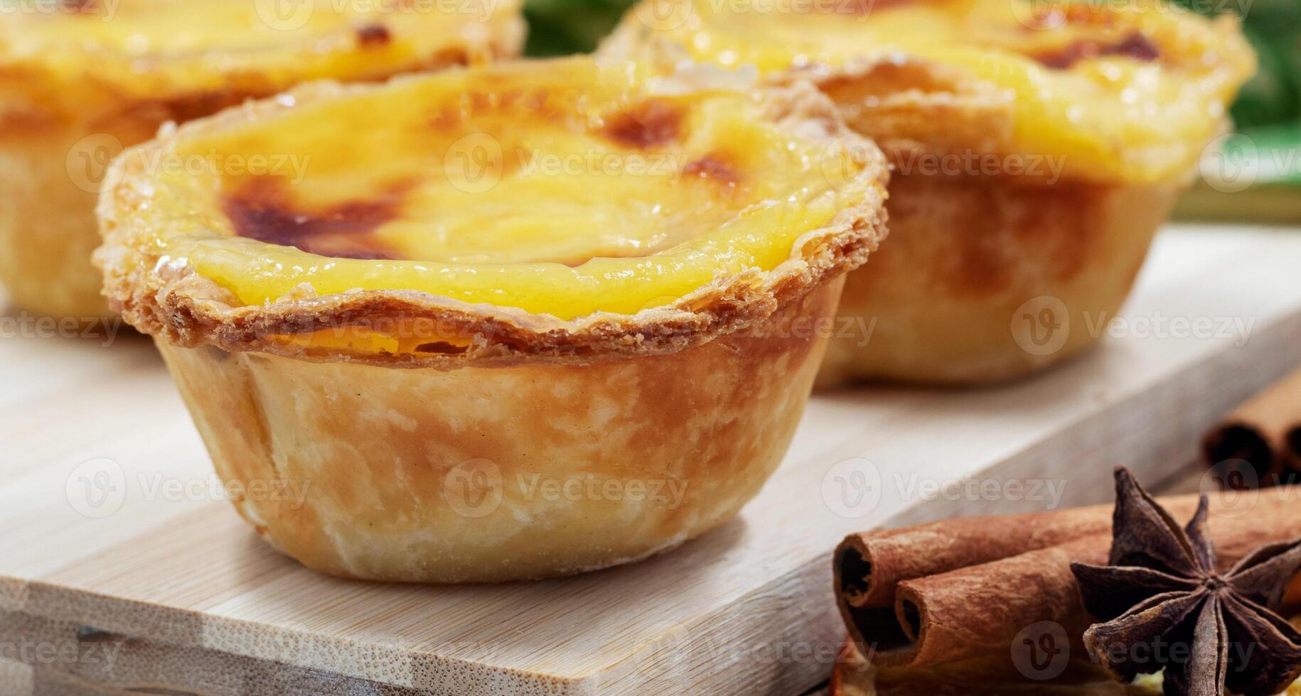 Pastel de nata tarts or Portuguese egg tart on a wooden brown background. Pastel de Belem is a small pie with a crispy puff pastry crust and a custard cream filling. Sweet dessert. photo