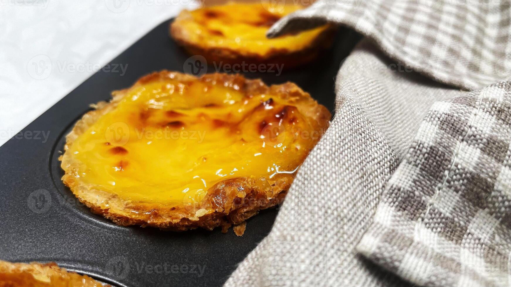 Lots of freshly baked Pastel de nata or Portuguese egg tart desserts in a baking dish. Pastel de Belme is a small pie with a crispy puff pastry crust and a custard filling. Small cupcake. photo