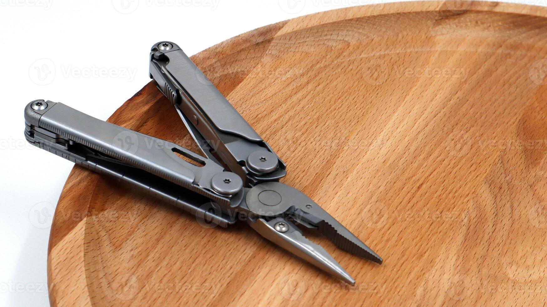 One modern open folding multifunctional knife made of gray iron on a wooden background. Multitool with extended tools and pliers. Compact and portable product. Pocket knife. EDC concept. photo