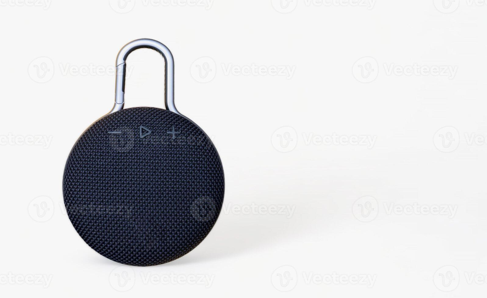 Waterproof round black speaker with carabiner. Digital music and sound concept. Mini, suitable for travel. Modern technology concept. Smart portable wireless speaker on a white background. photo