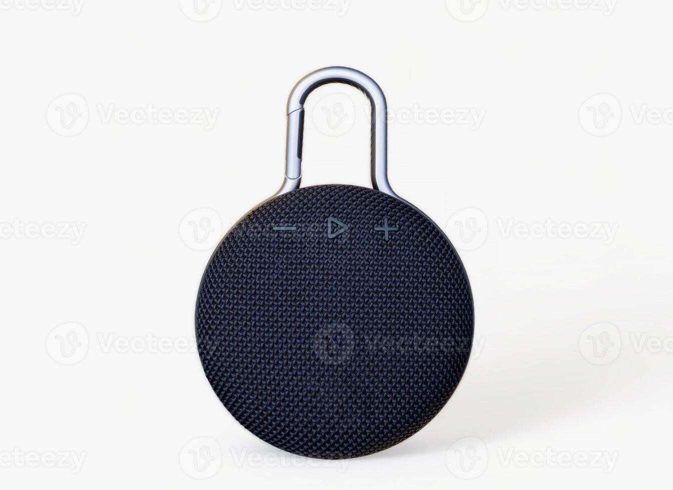 Waterproof round black speaker with carabiner. Digital music and sound concept. Mini, suitable for travel. Modern technology concept. Smart portable wireless speaker on a white background. photo