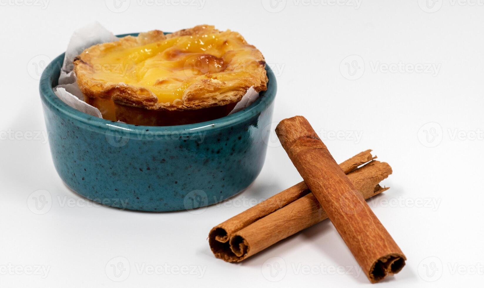 Pastel de nata tarts or Portuguese egg tart and cinnamon sticks isolated on white background. Pastel de Belem is a small pie with a crispy puff pastry crust and a custard cream filling. photo