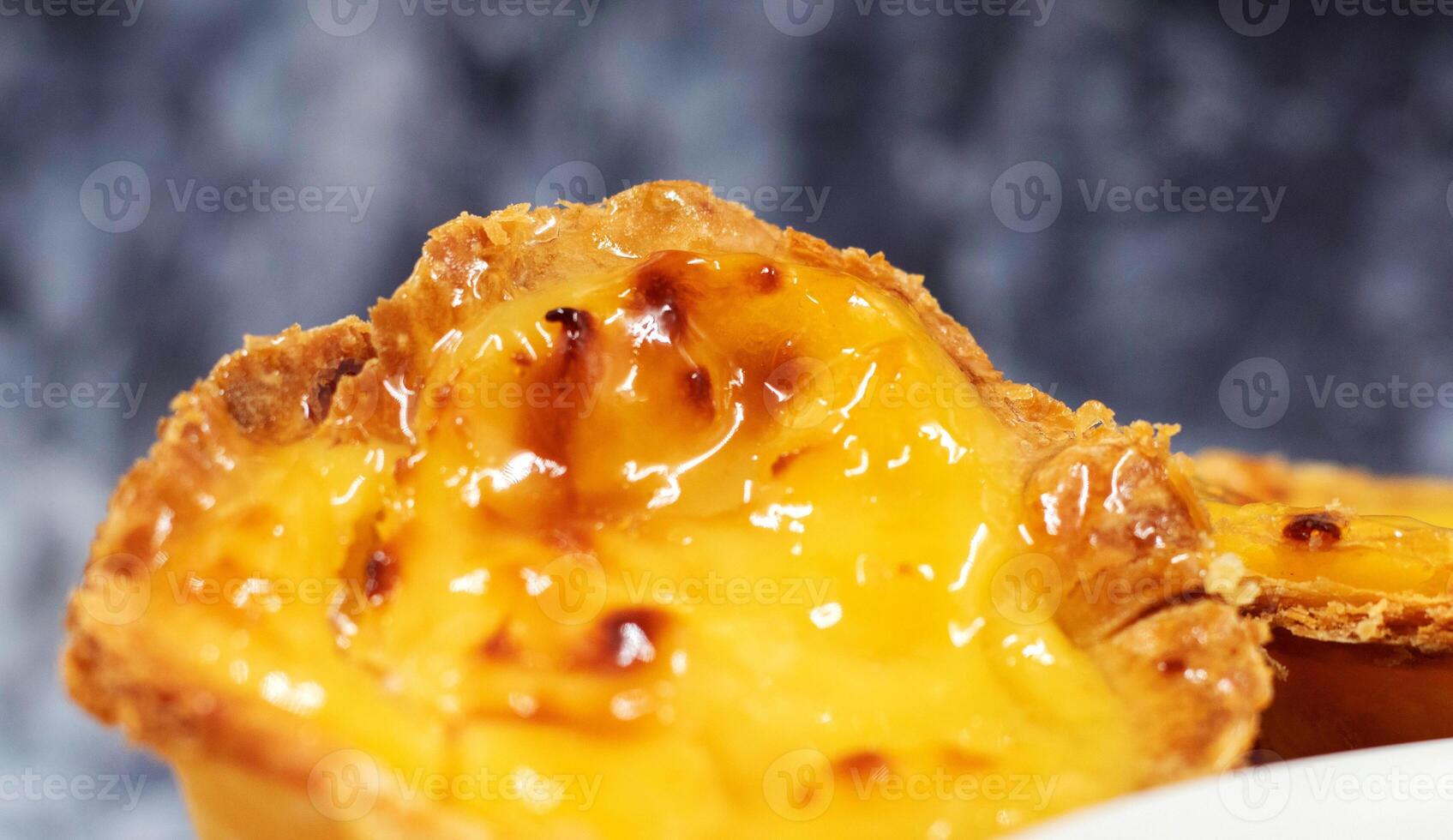 One freshly baked dessert Pastel de nata or Portuguese egg tart close up. Pastel de Belm is a small pie with a crispy puff pastry crust and a custard cream filling. A small dessert, a cupcake. photo