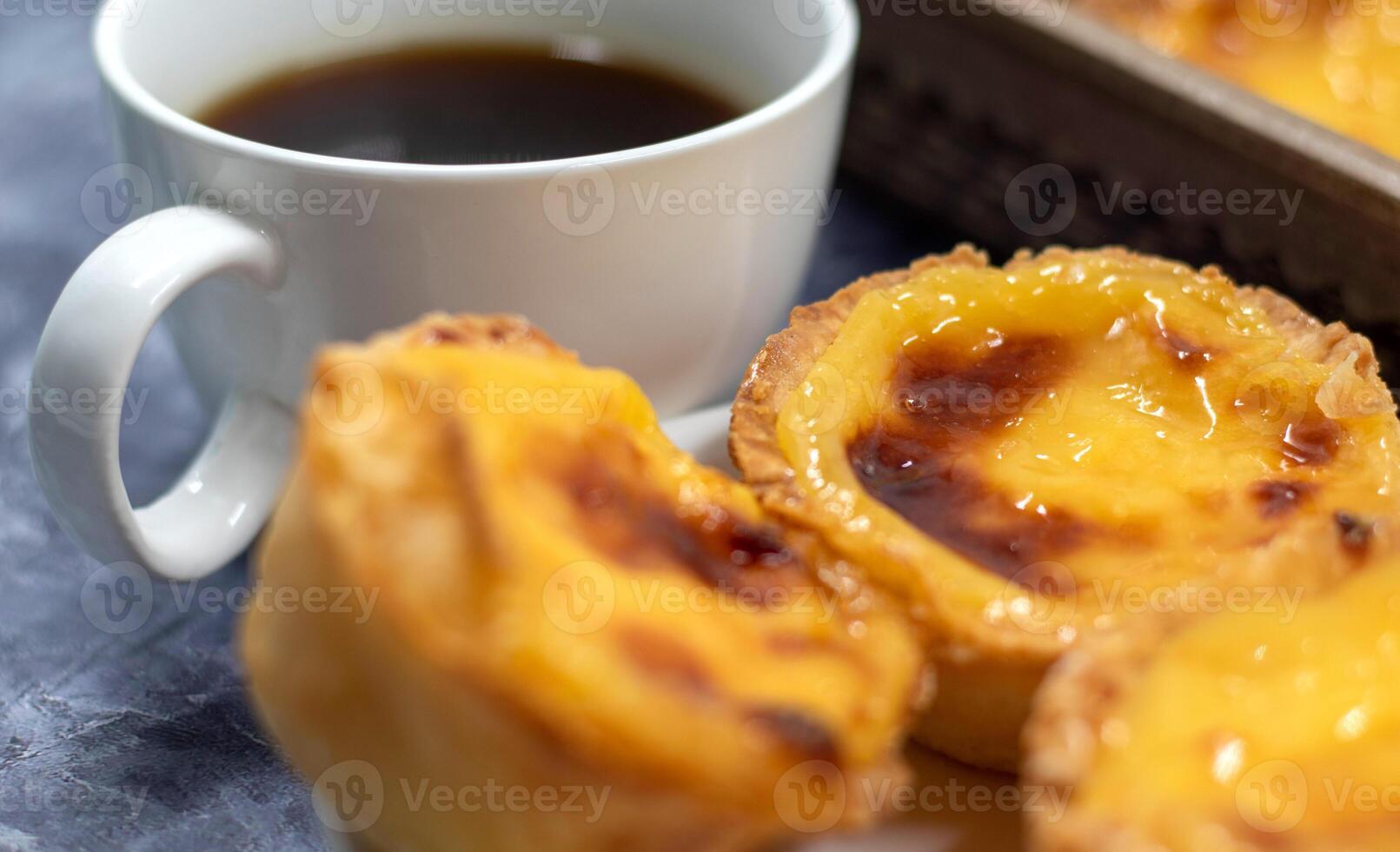 Lots of desserts Pastel de nata or Portuguese egg tart with a white cup of black coffee. Pastel de Belm is a small pie with a crispy puff pastry crust and a custard cream filling. photo