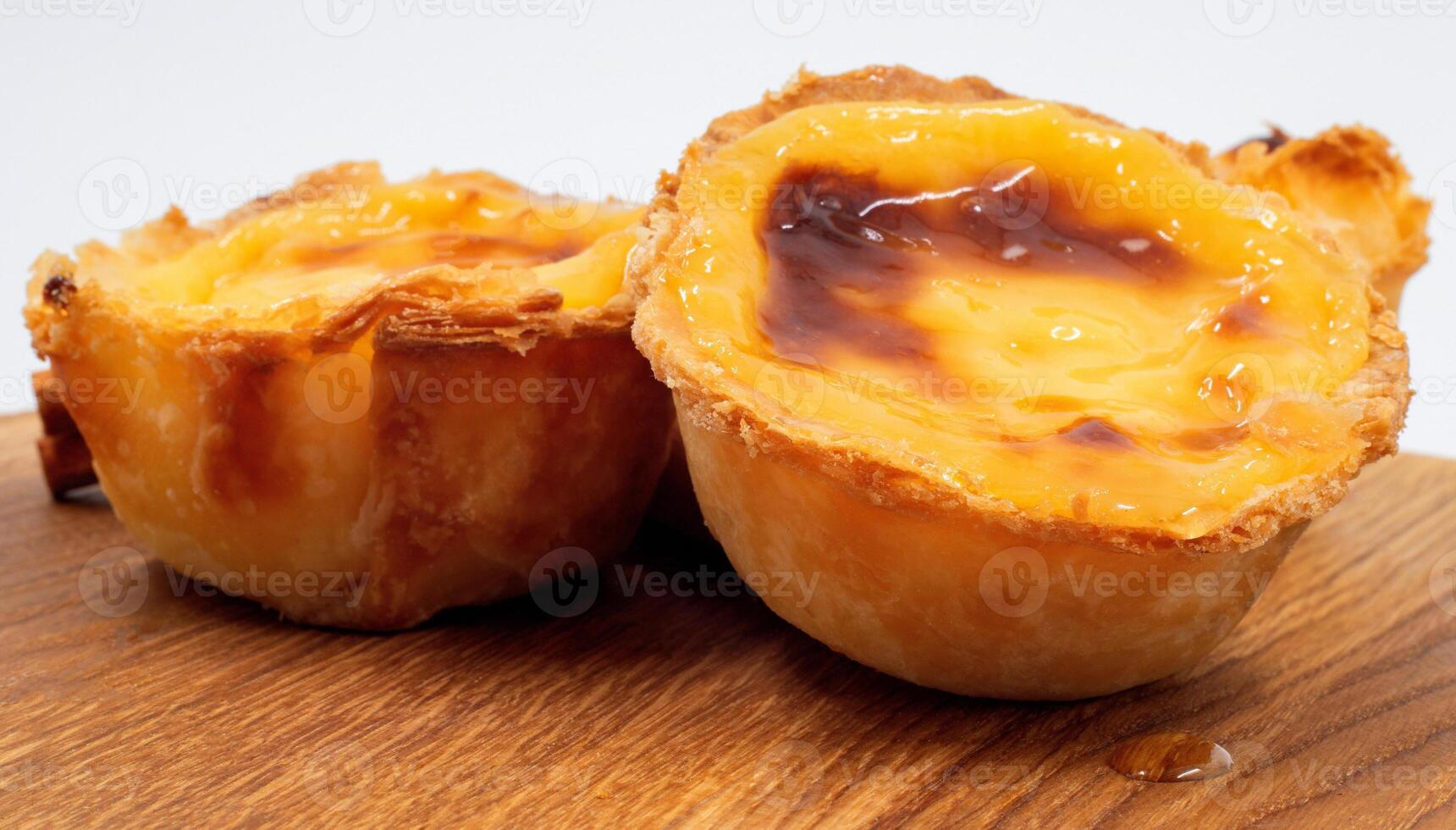 Pastel de nata tarts or Portuguese egg tart on a wooden brown background. Pastel de Belem is a small pie with a crispy puff pastry crust and a custard cream filling. Sweet dessert. photo
