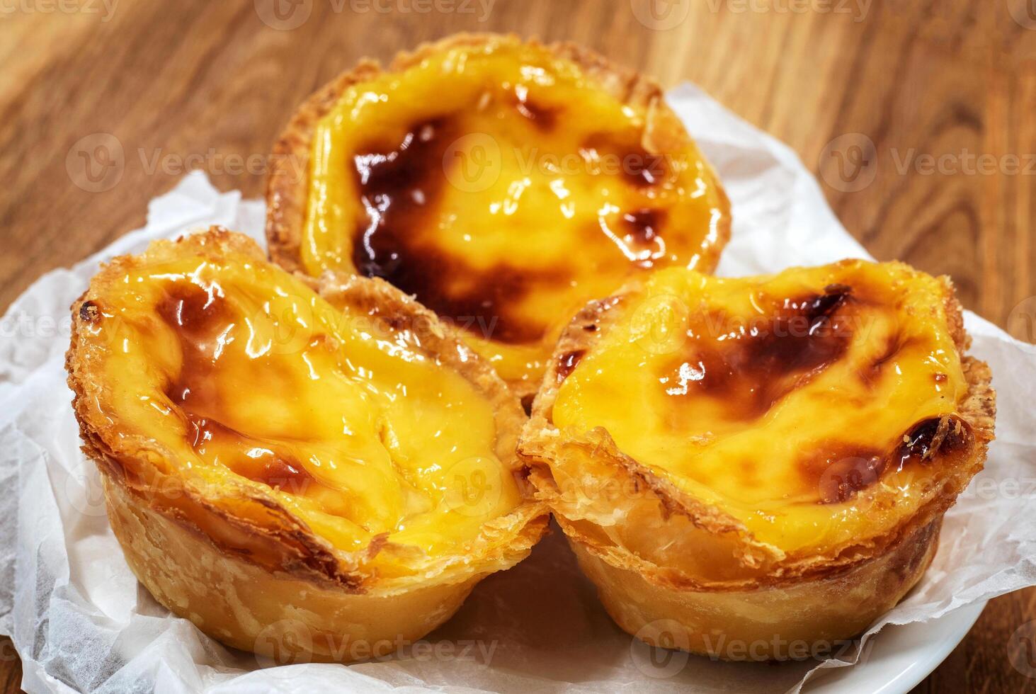 Pastel de nata tarts or Portuguese egg tart on a wooden brown background. Pastel de Belem is a small pie with a crispy puff pastry crust and a custard cream filling. Sweet dessert. photo