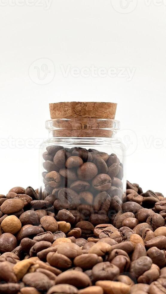 Coffee beans in a small glass jar with a cork lid on the table. Coffee beans packed in a transparent, airtight storage container. Coffee seeds inside a glass jar. photo