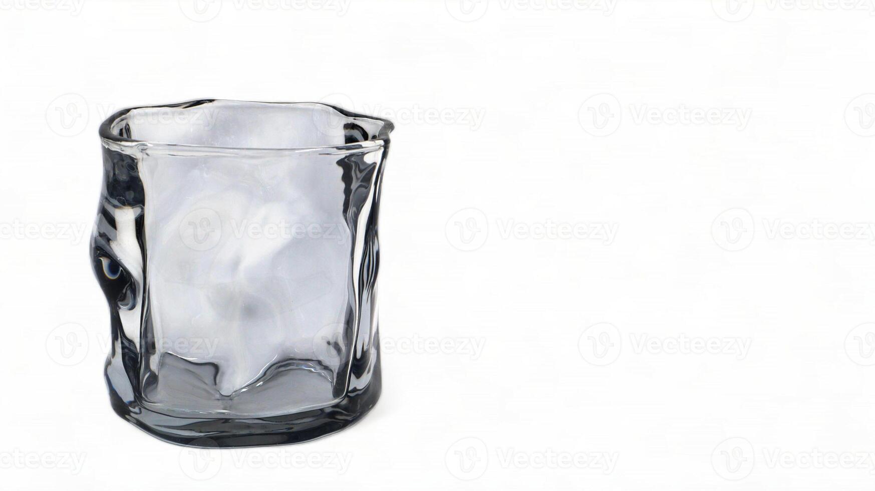 One empty curved glass glass isolated on white background. Crooked dishes. photo