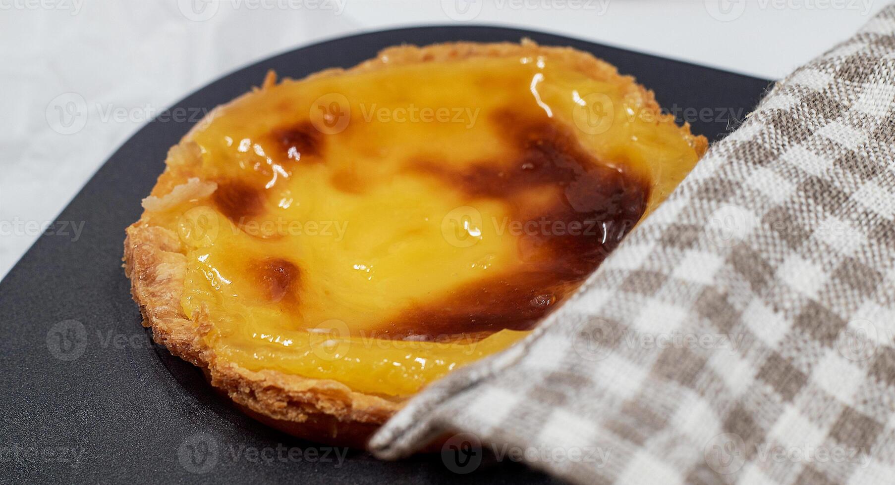 One freshly baked Pastel de nata or Portuguese egg tart in a baking dish. Pastel de Belm is a small pie with a crispy puff pastry crust and a custard cream filling. A small dessert, a cupcake. photo