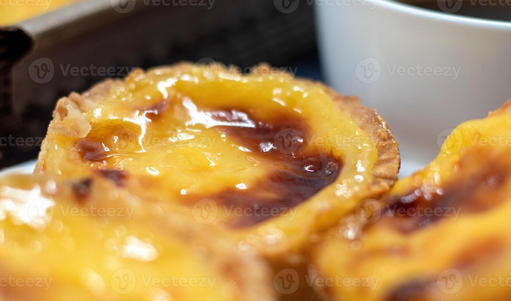 Lots of desserts Pastel de nata or Portuguese egg tart with a white cup of black coffee. Pastel de Belm is a small pie with a crispy puff pastry crust and a custard cream filling. photo