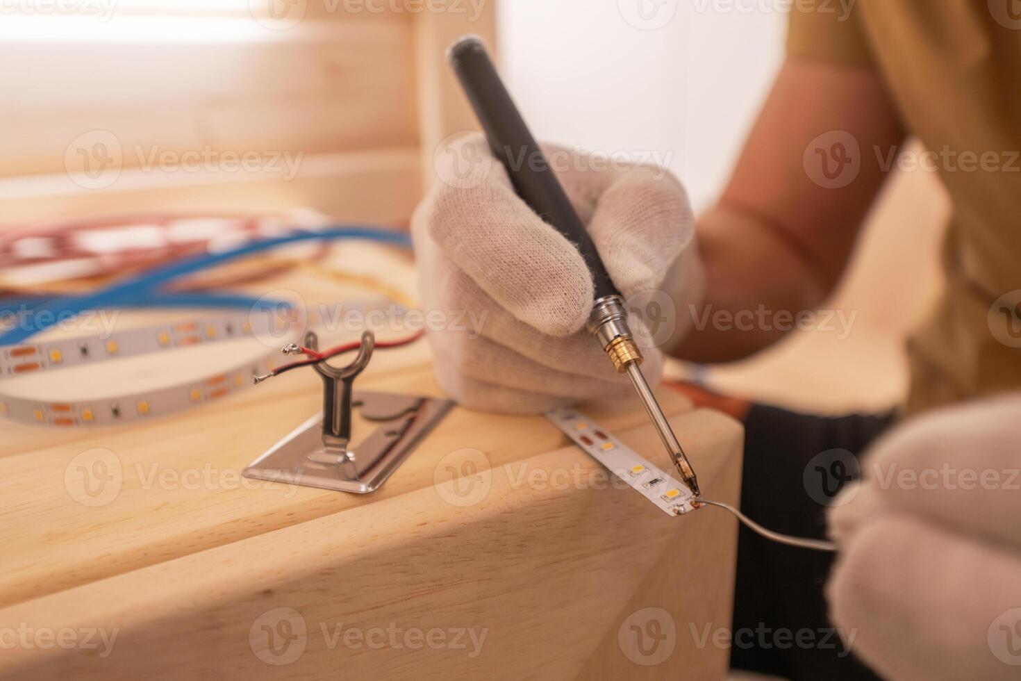 Electrician with Soldering Iron Attaching LED Stripe Cable photo
