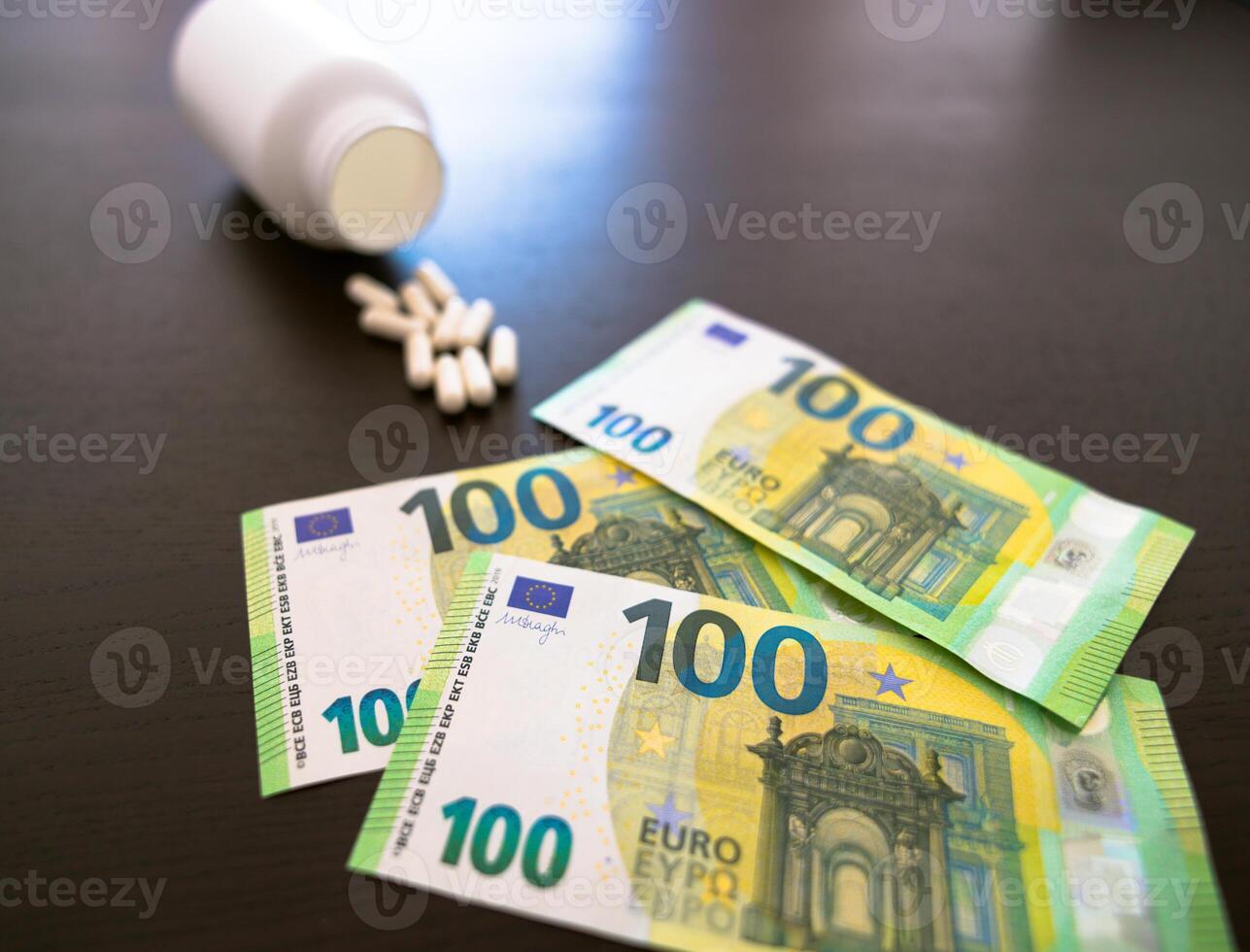 A jar of tablets on a black table. 100 euros in paper banknotes. photo