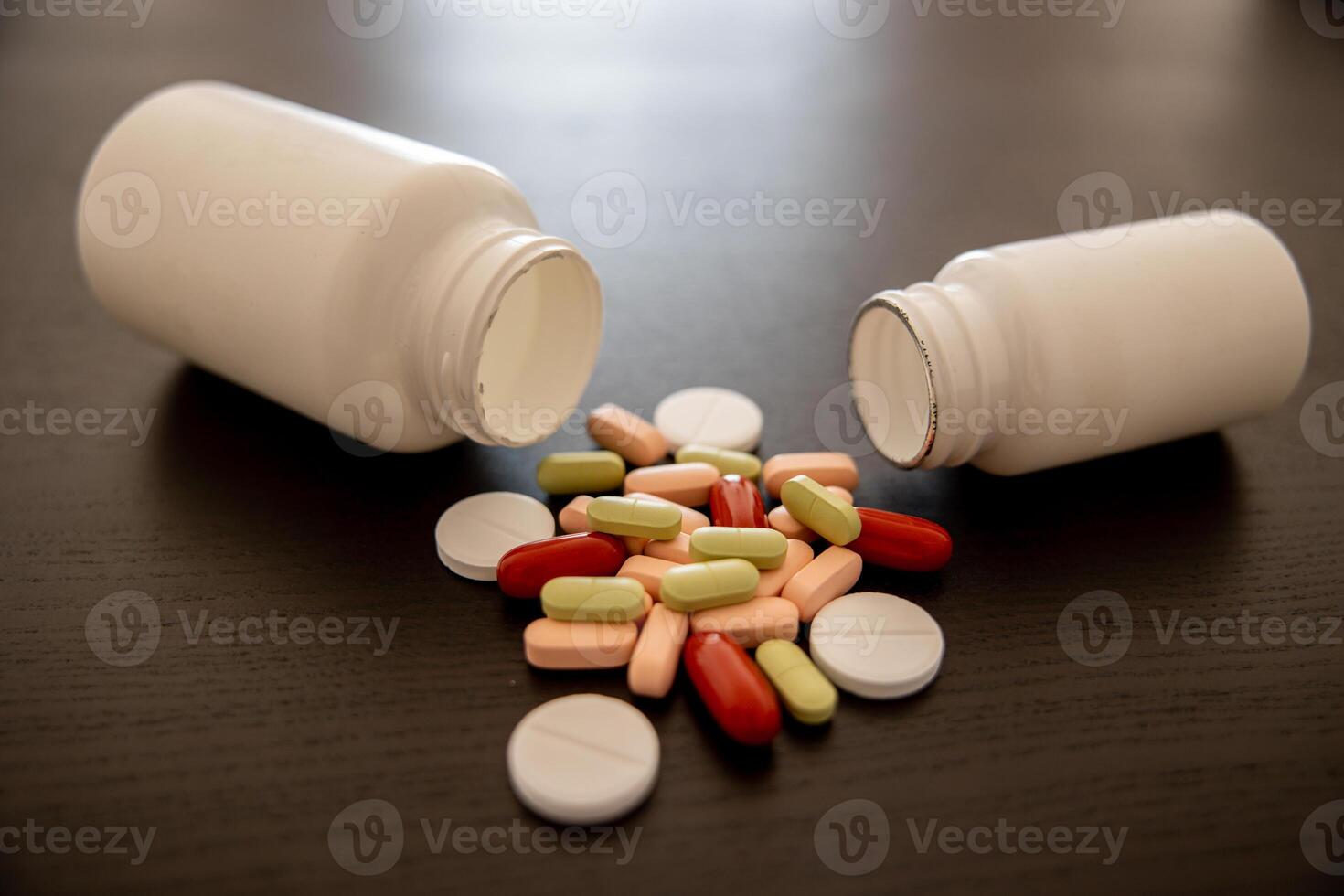 Jars of medicines Scattered aspirin tablets Green pink and red tablets photo