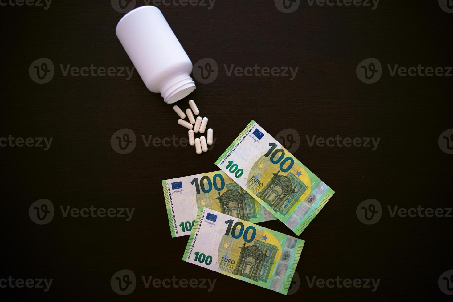 A jar of tablets on a black table. 100 euros in paper banknotes. photo