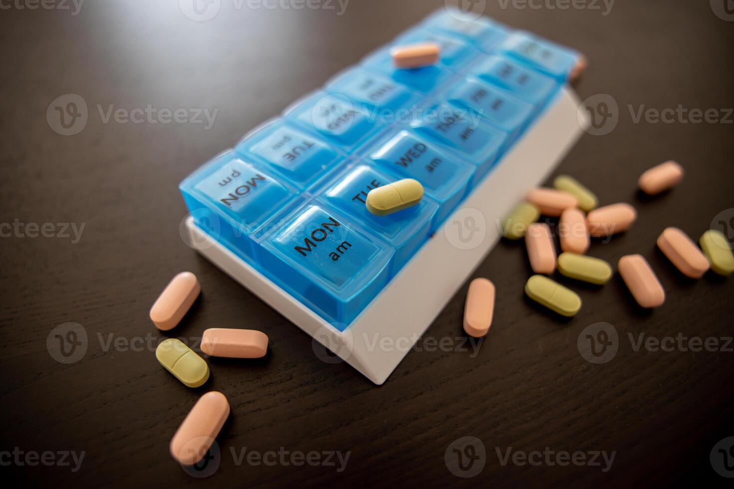 Blue tablet on a black table with scattered green and pink pills photo