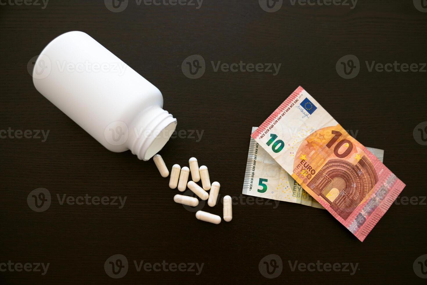 Jar with tablets, medicinal capsules on a black table. euros paper banknotes photo