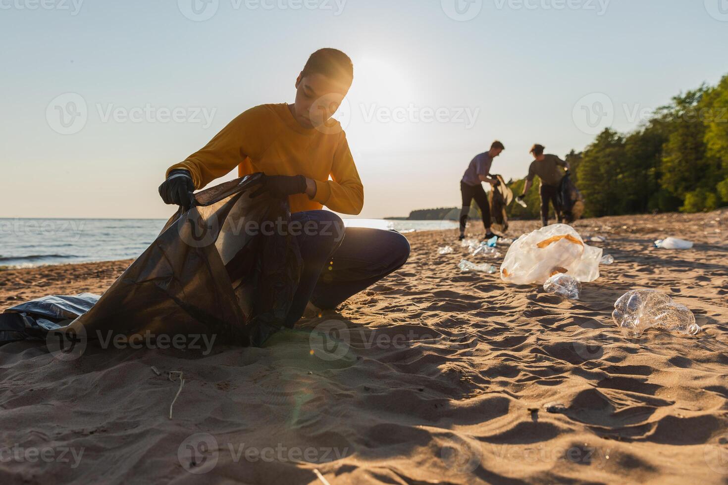 Earth day. Volunteers activists collects garbage cleaning of beach coastal zone. Woman and mans puts plastic trash in garbage bag on ocean shore. Environmental conservation coastal zone cleaning photo