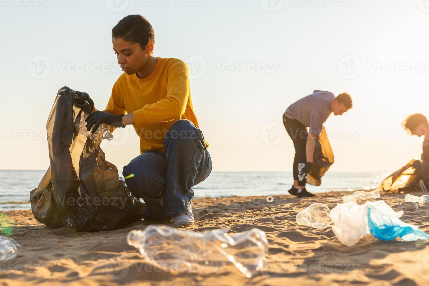 Earth day. Volunteers activists collects garbage cleaning of beach coastal zone. Woman and mans puts plastic trash in garbage bag on ocean shore. Environmental conservation coastal zone cleaning photo