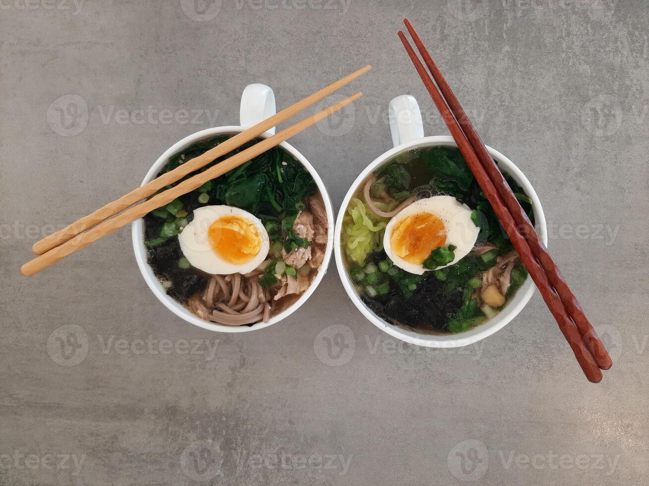 Asian ramen soba noodle soup close up with chicken, boiled egg, nori, green spinach and green onion served with chopsticks. Top view. photo