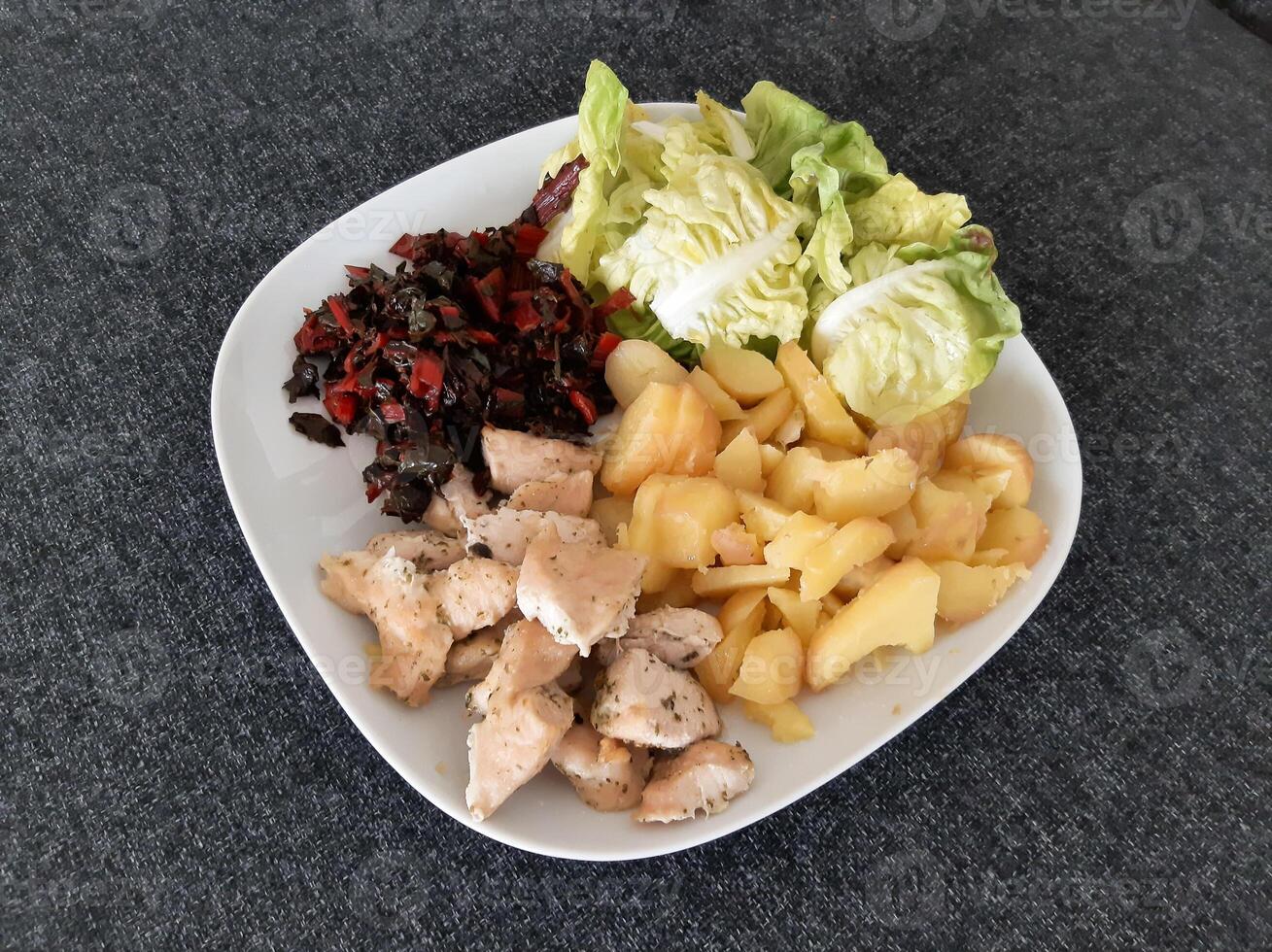 hecho en casa A la parrilla pollo con hervido patatas, verde ensalada, y ruibarbo servido en un blanco plato foto