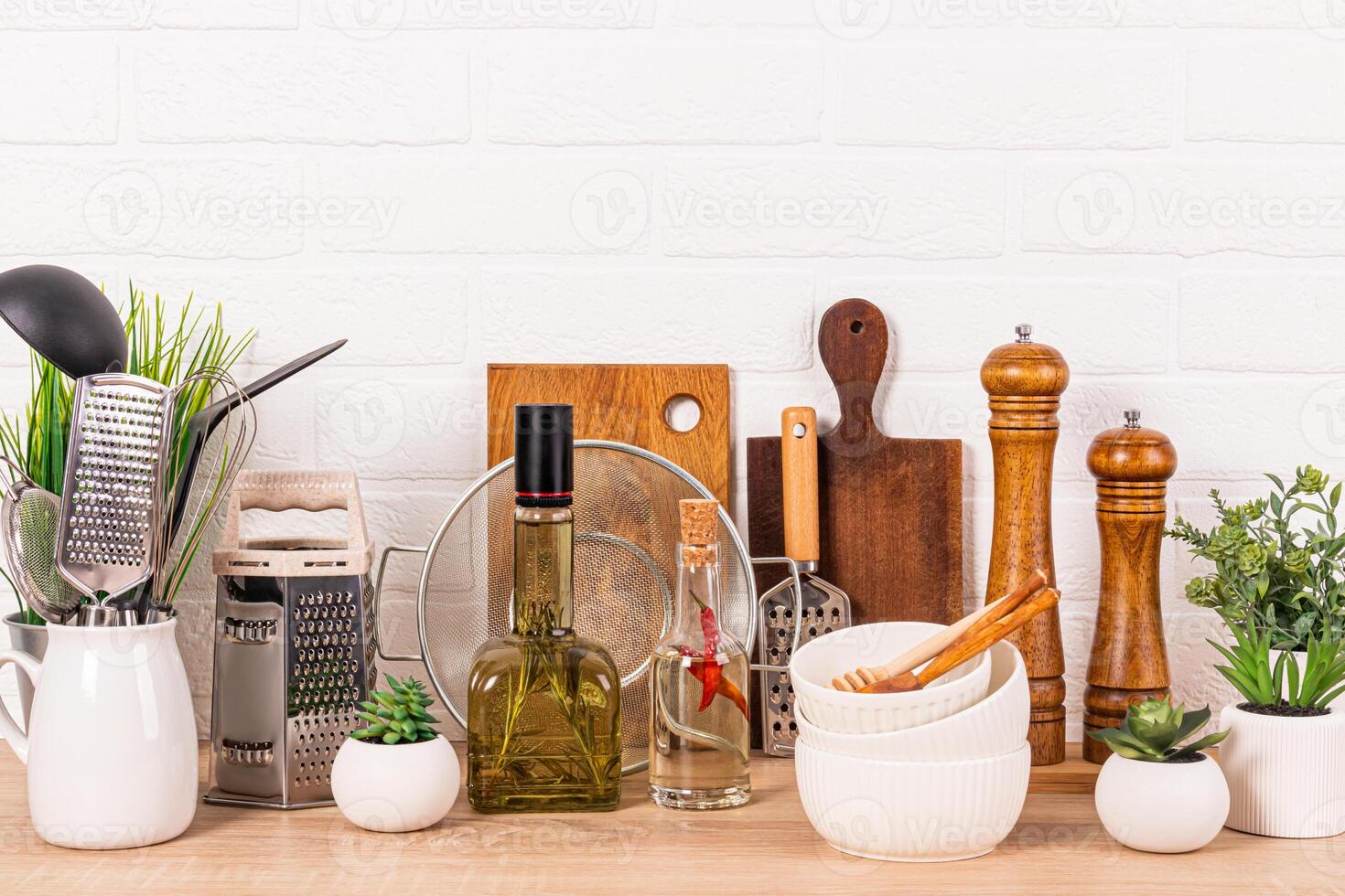 Lots of different kitchen utensils, oil bottles, spice mill and potted plants. A modern look of the kitchen space. Eco-friendly cuisine. photo
