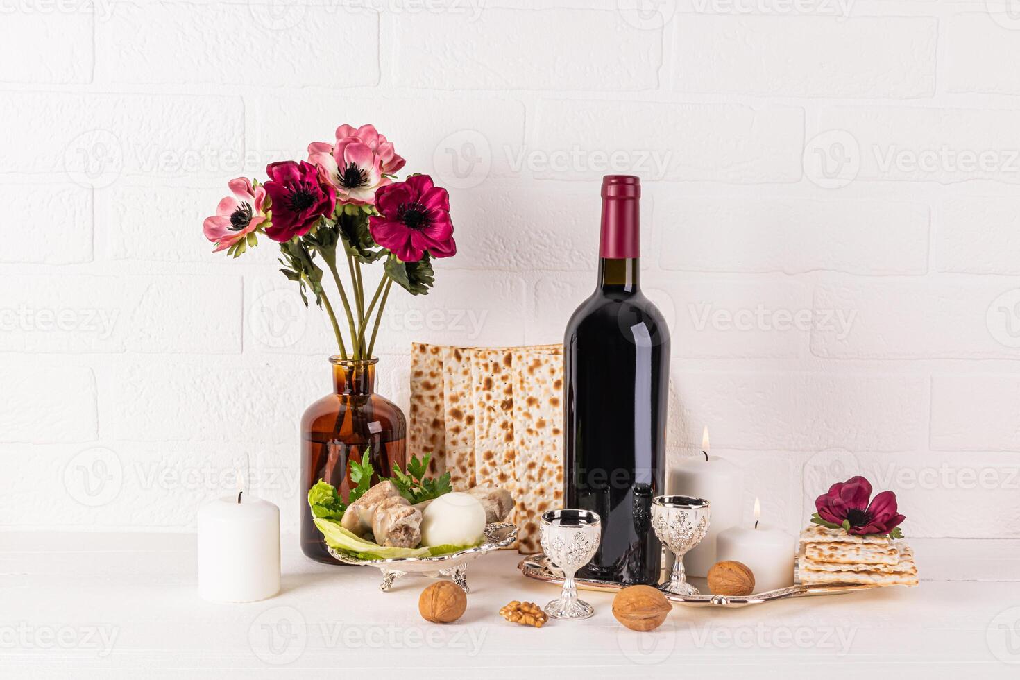 Beautiful festive still life for the Jewish Passover holiday. Front view of traditional foods, kosher wine in glass bottle , candles. photo
