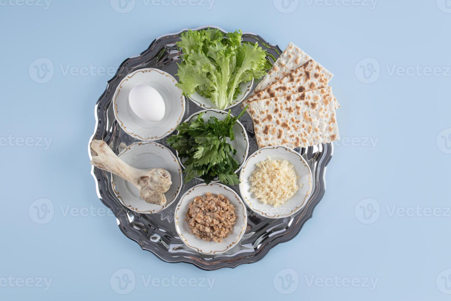 A beautiful silver Seder dish with traditional treats for the spring holiday of Jewish Passover. Top view. Blue background. A copy the space. photo
