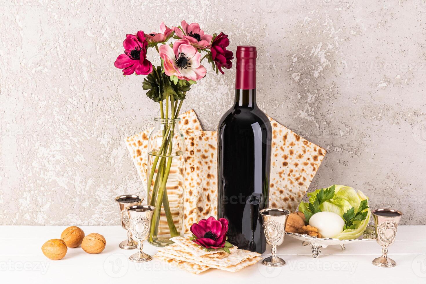 festivo todavía vida para el primavera judío fiesta de Pascua. tradicional comestible según la ley judía alimento, un botella de rojo vino y plata Disparo lentes con vertido vino foto