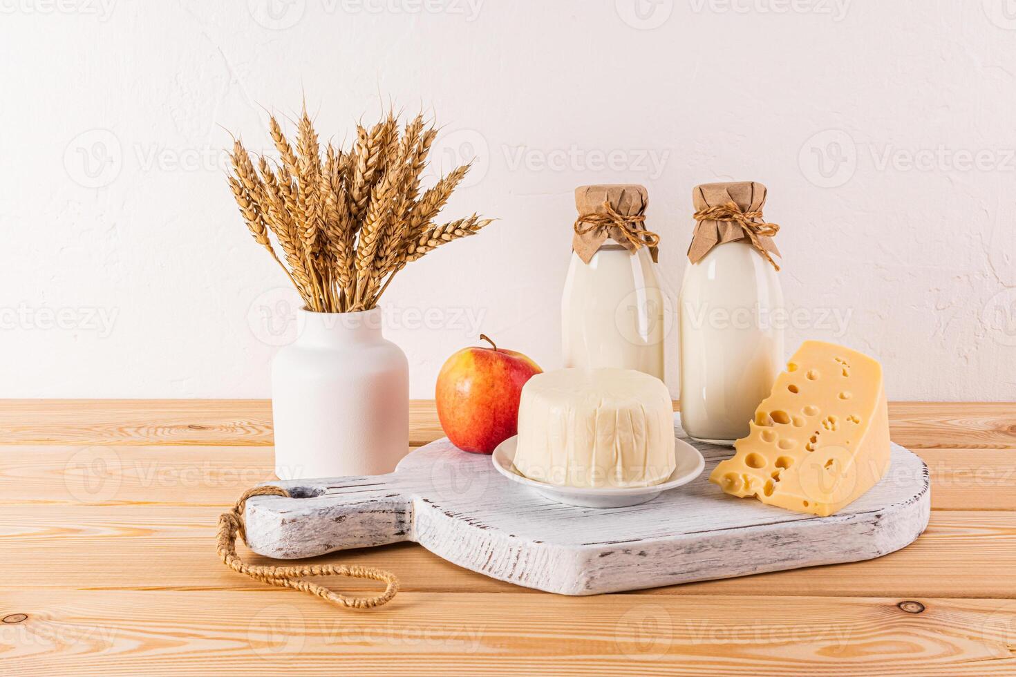 A fresh dairy products cheese, milk, apples and ears of corn in a vase for the holiday of Jewish Shavuot. Front view. photo