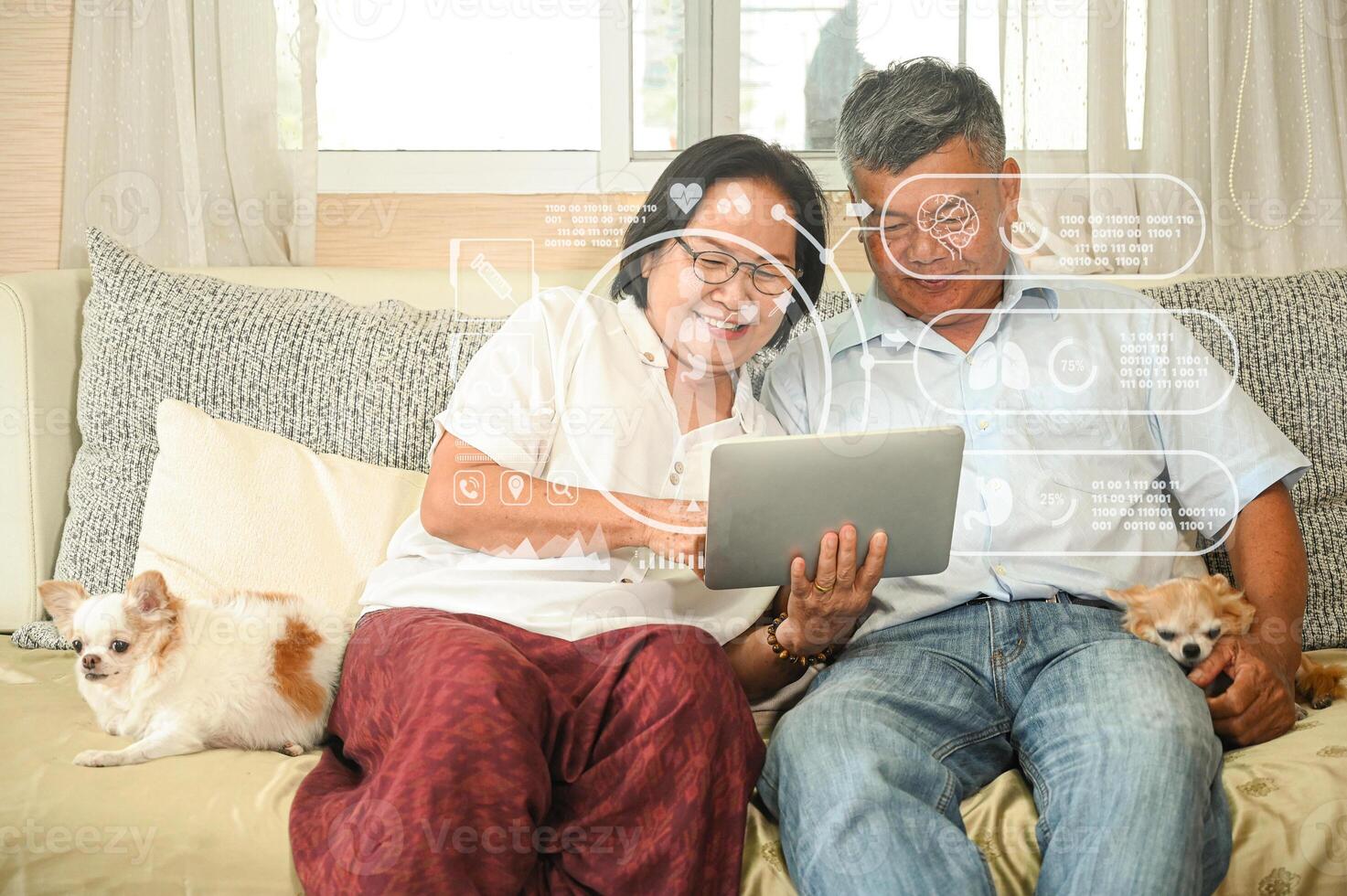 Elderly woman and an asian man sitting on a sofa are using a tablet. photo