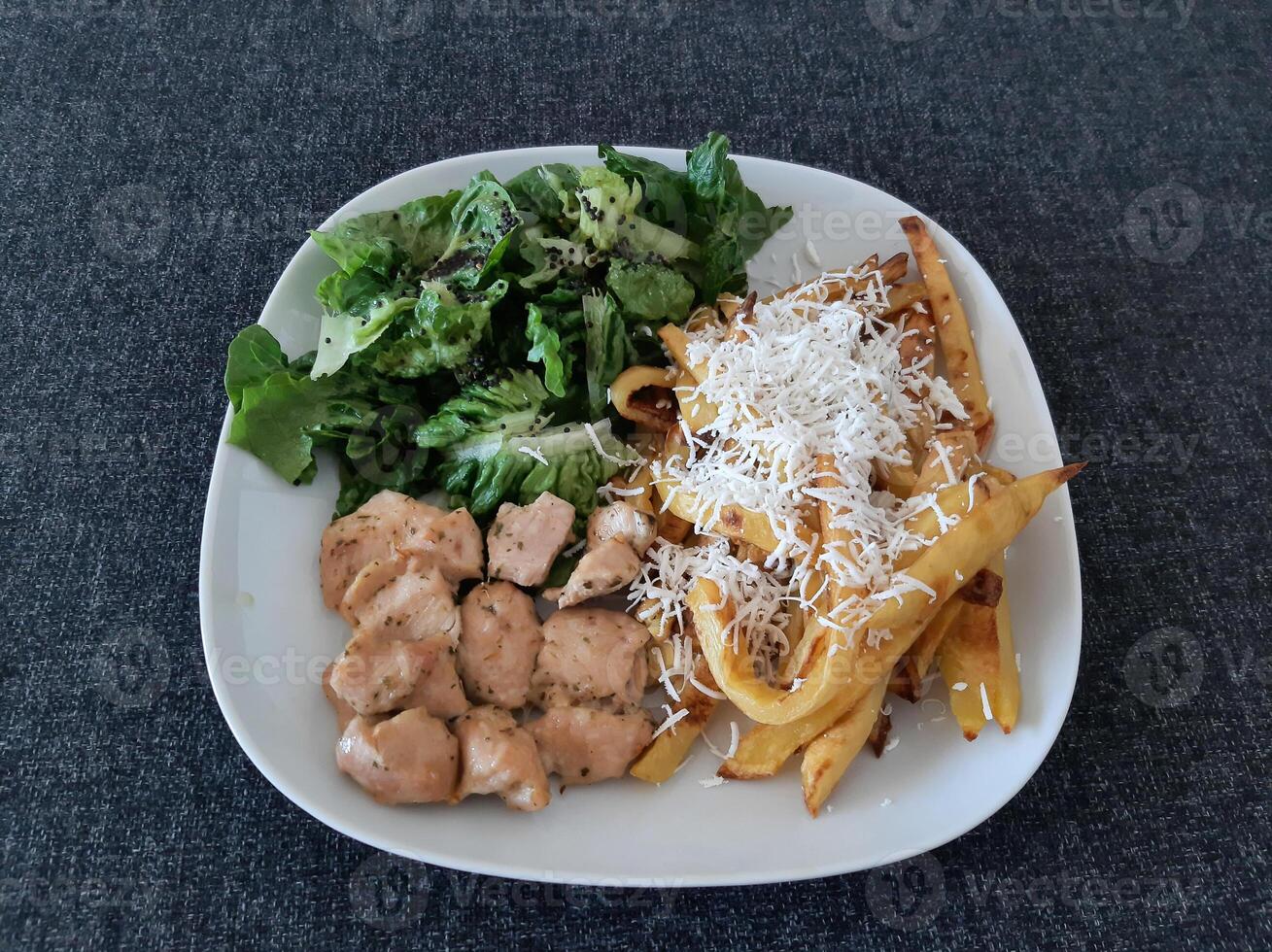 Homemade grilled chicken with french fries, cheese and green salad, served on a white plate photo