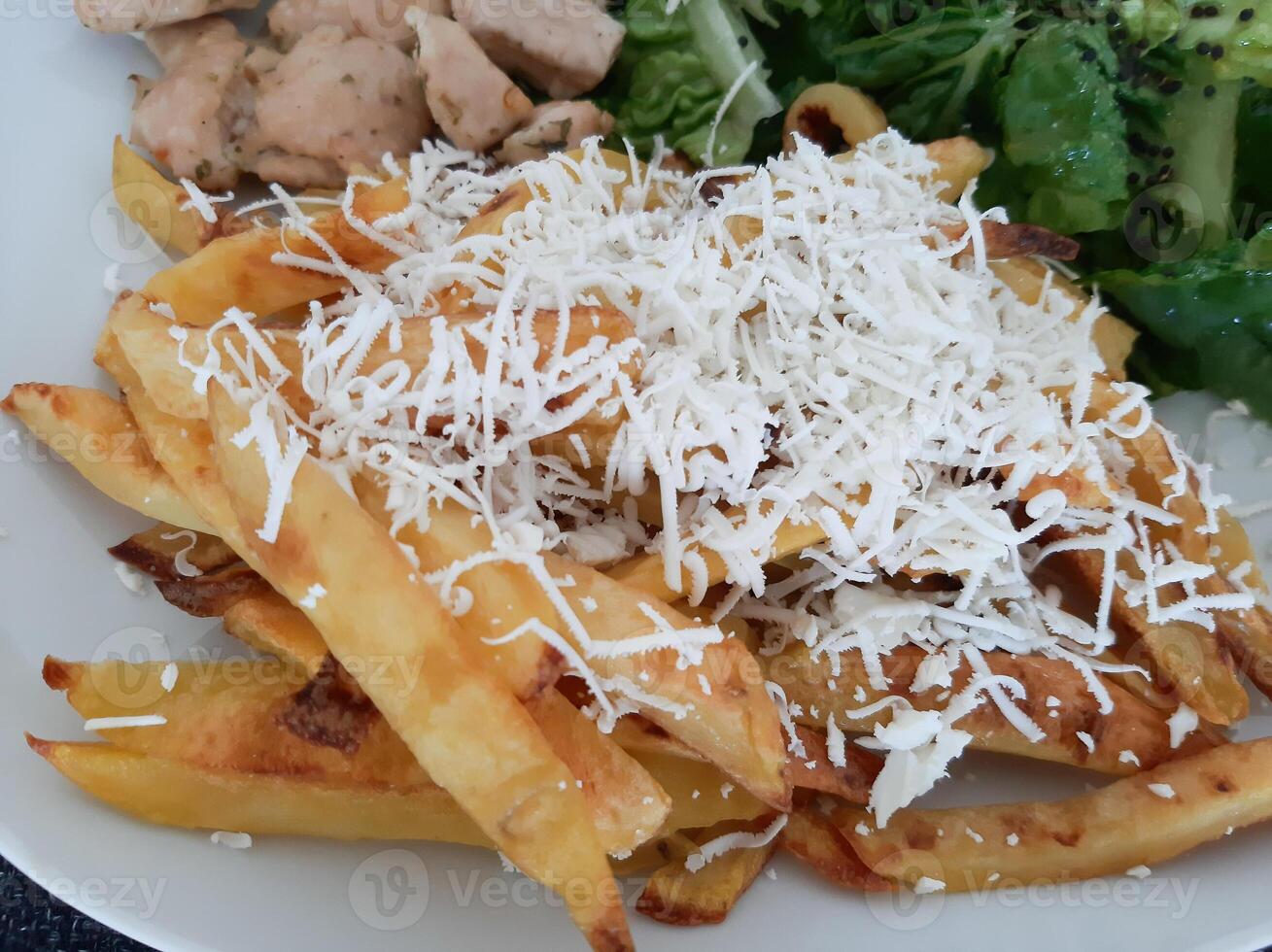 Homemade grilled chicken with french fries, cheese and green salad, served on a white plate photo