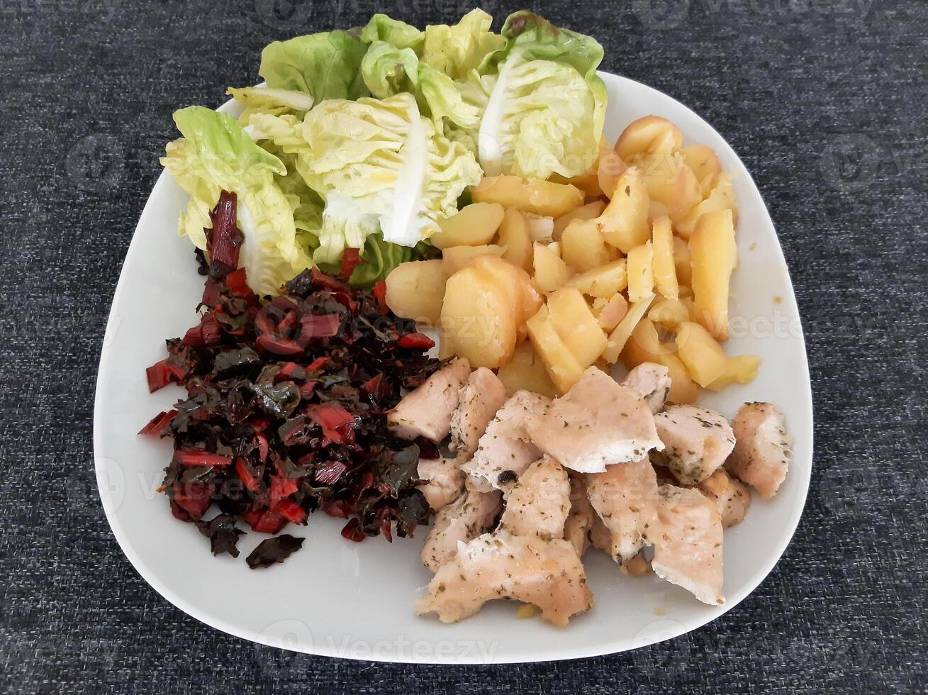 Homemade grilled chicken with boiled potatos, green salad, and rhubarb served on a white plate photo