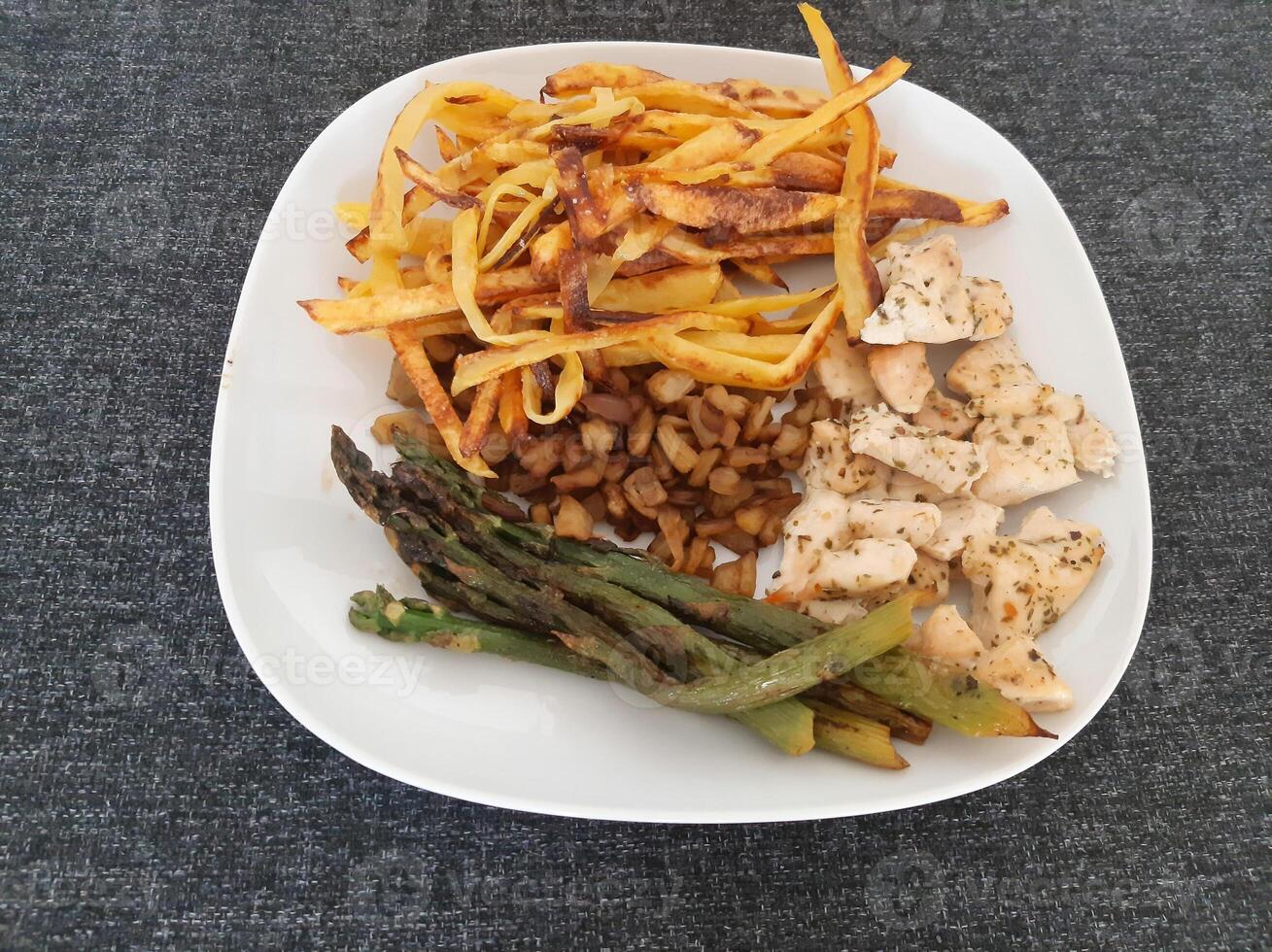 Homemade grilled chicken with french fries, eggplant and grilled asparagus, served on a white plate photo