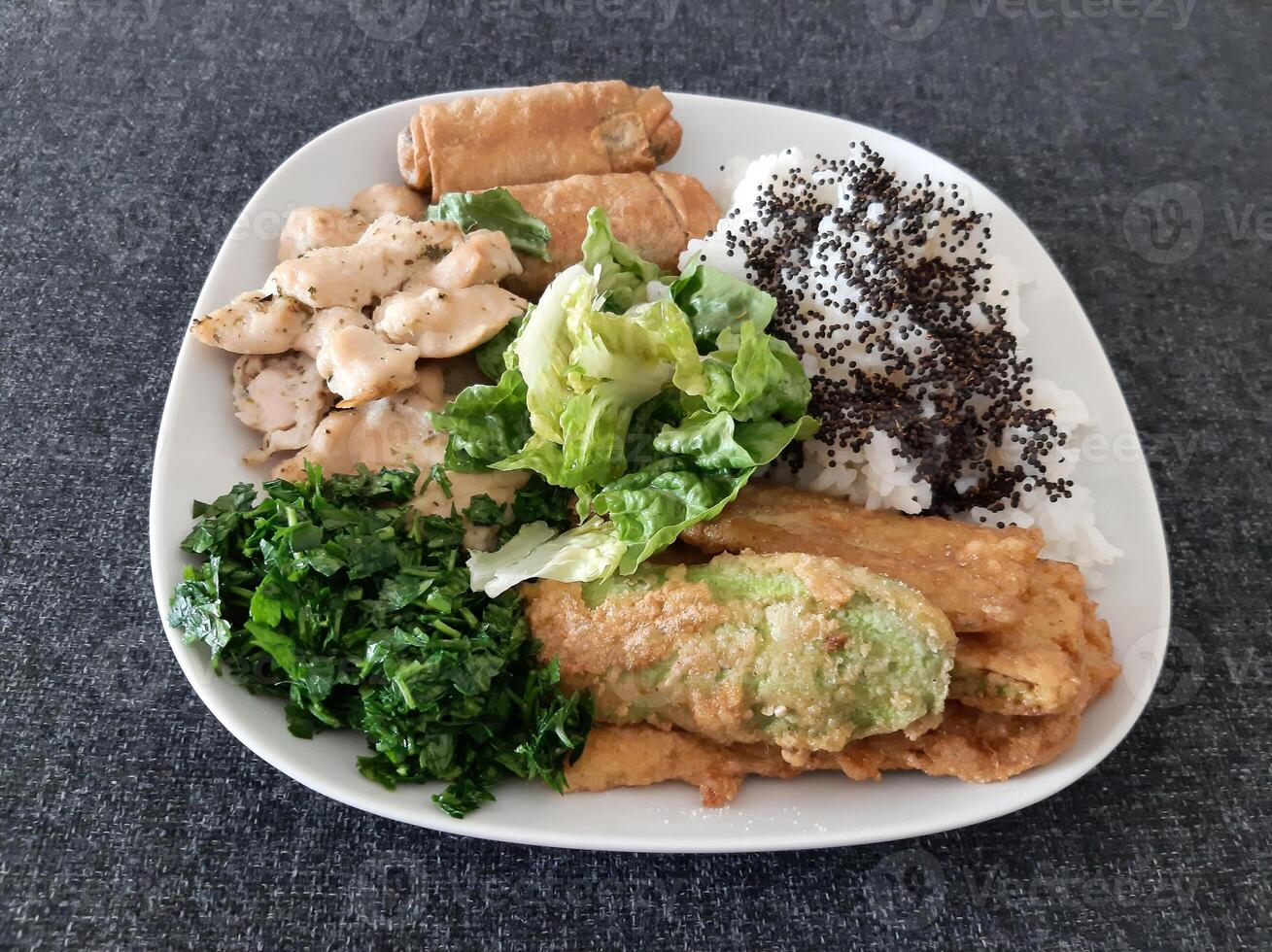 Homemade grilled chicken with grilled zucchini, green salad, spring rolls, rice pilaf and parsley. Broccoli seeds on top of the rice pilaf. photo