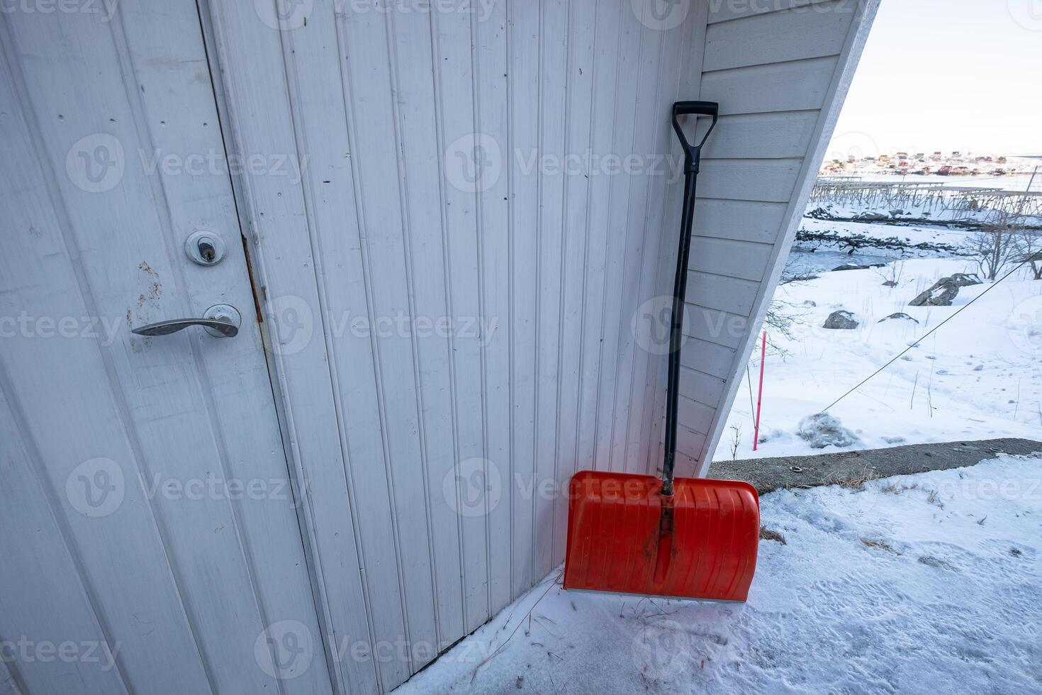 Snow shovel put on front of wooden house photo