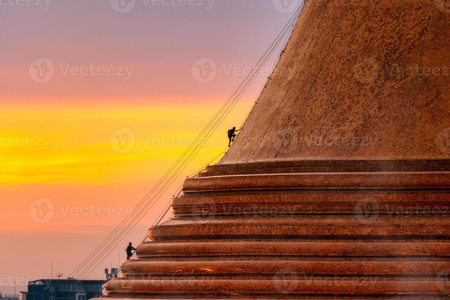 Buddhists climb up to light decoration the golden pagoda Phra Pathom Chedi on sunset sky in annual festive at Nakhon Pathom photo