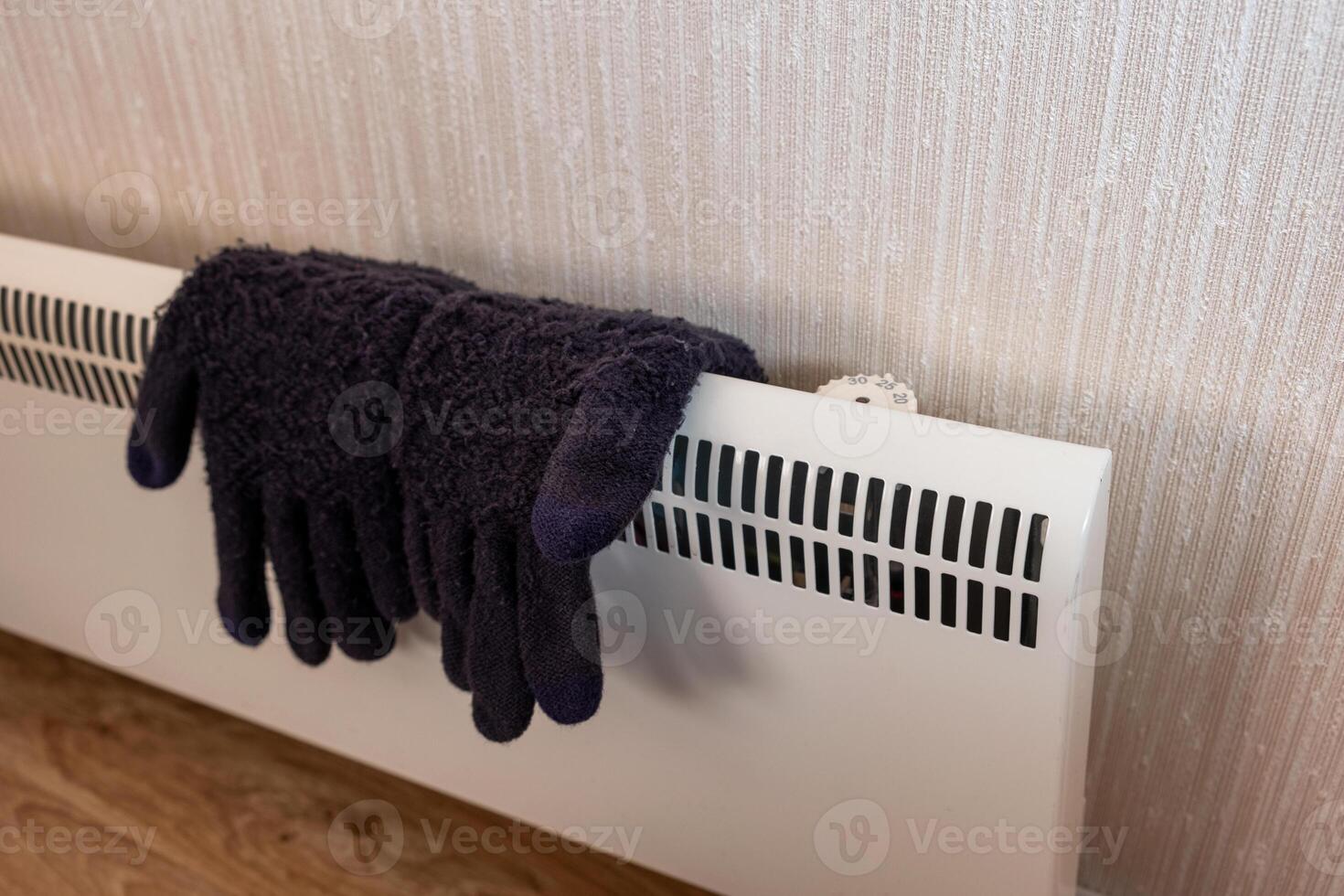 Knit winter gloves drying on heater photo