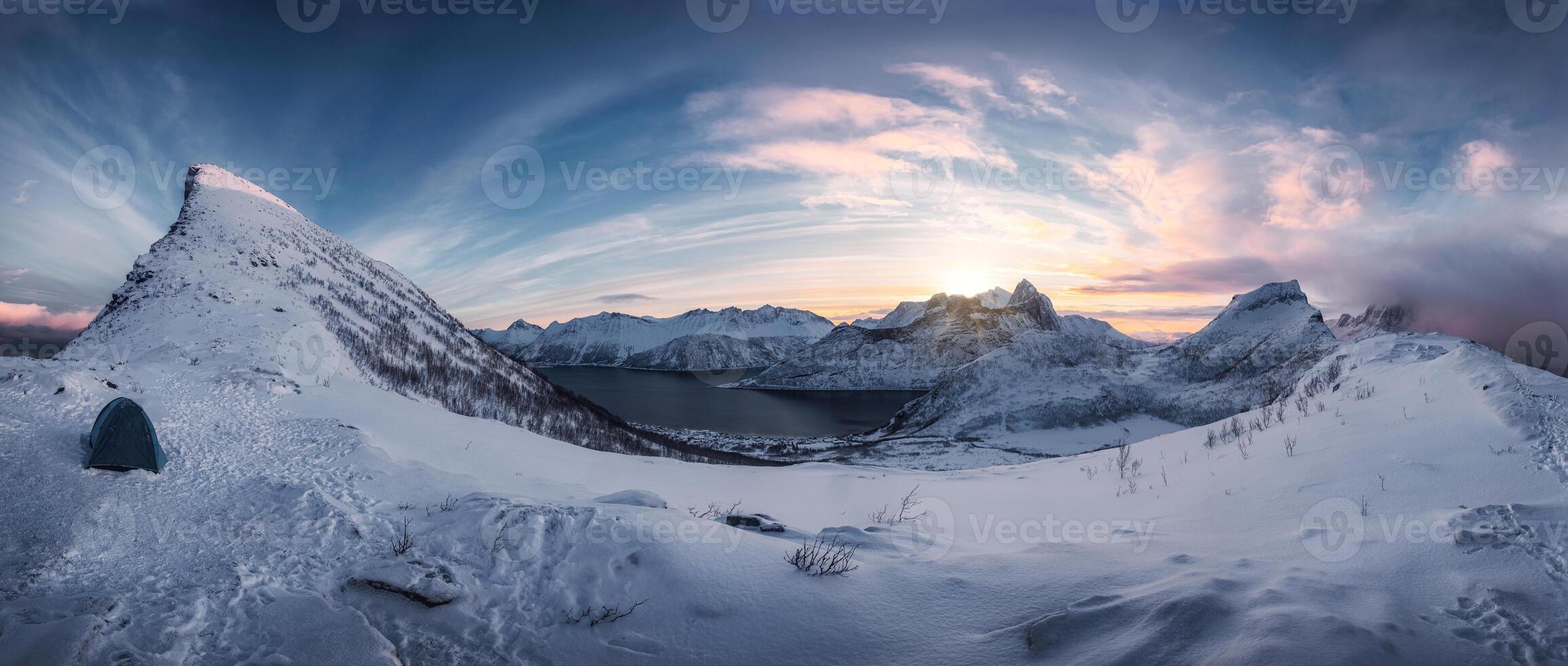 Hiking on snowy mountain range in sunrise on Segla peak at Senja Island photo