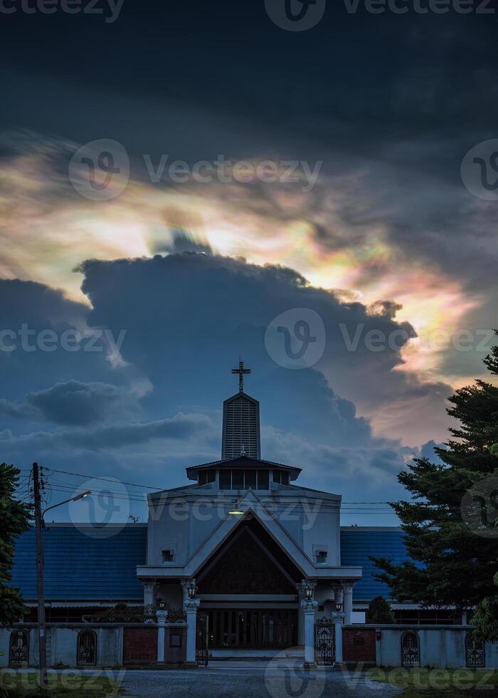 Mysterious cloud iridescence phenomenon glowing over christian church in the evening photo