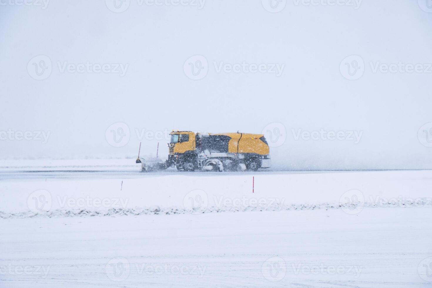 Yellow snow ploughs plowing snow cover road in blizzard photo