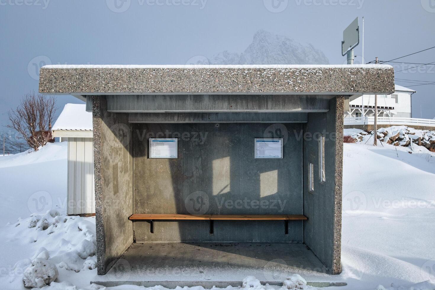 Nobody in concrete shelter bus stop and bench in snowing day photo