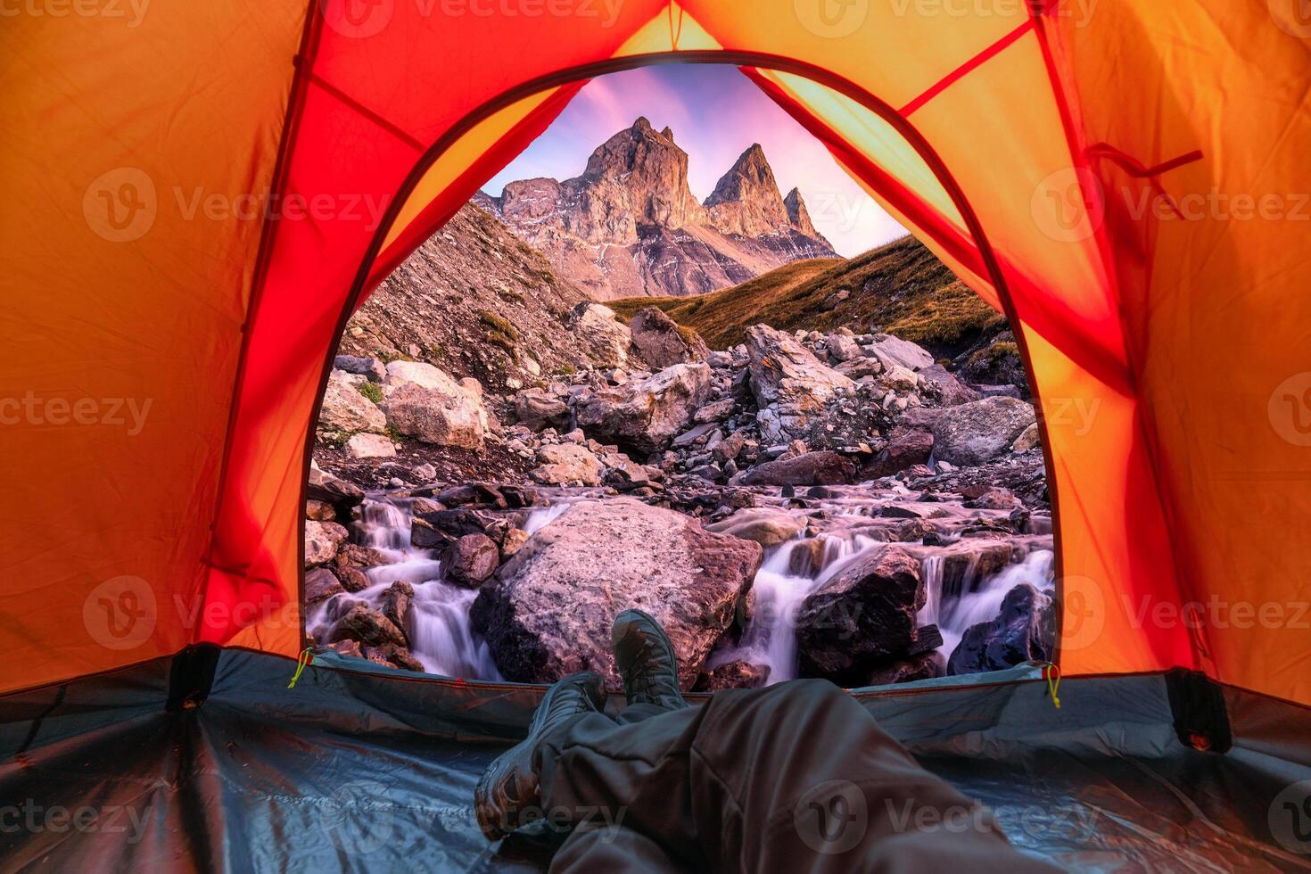 View from inside a tent of tourist relaxing and enjoying the Aiguilles d'Arves with iconic three mountain and waterfall rapids flowing in French Alps photo