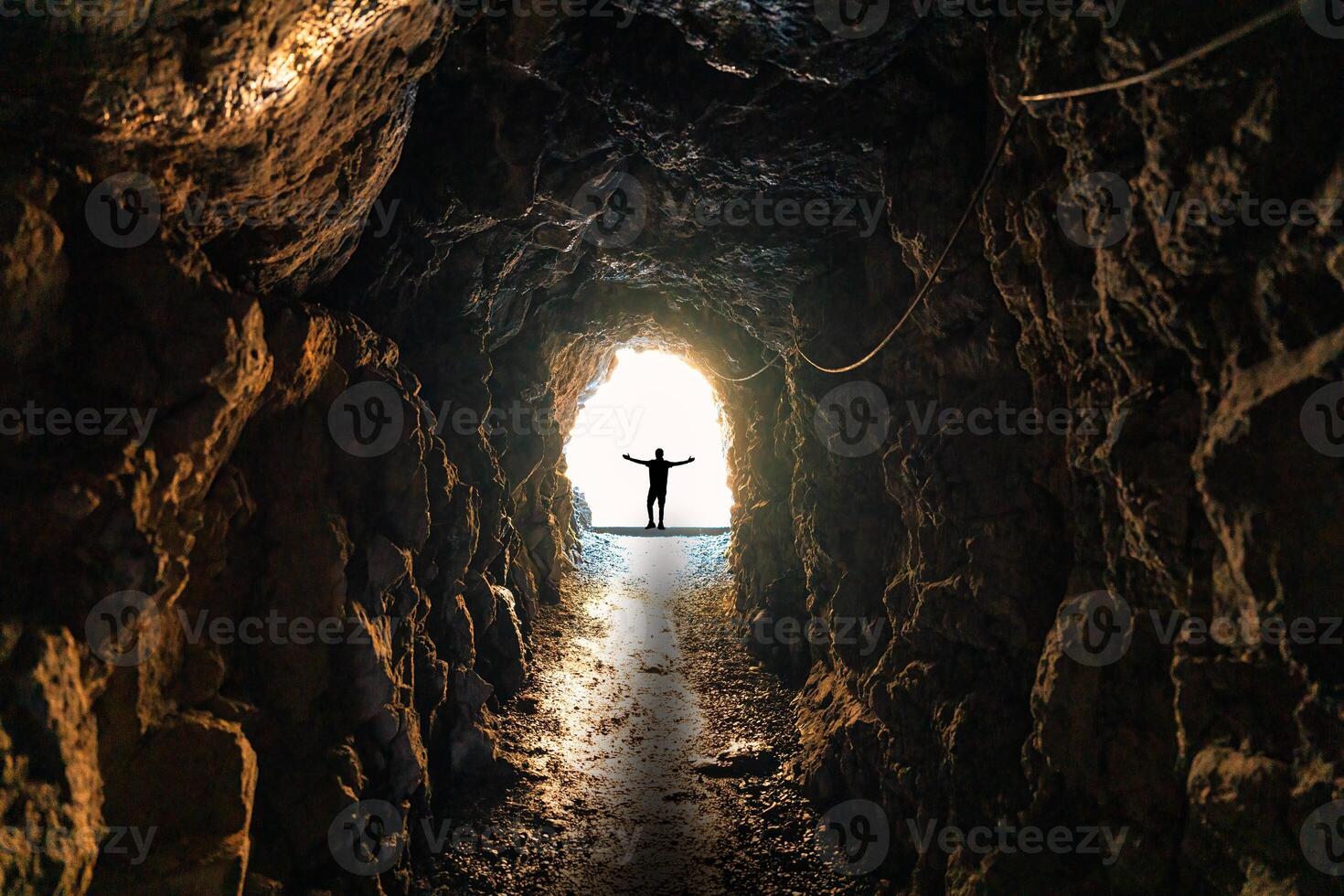 silueta hombre en pie en final de natural cueva, subterráneo túnel y ligero brilla foto