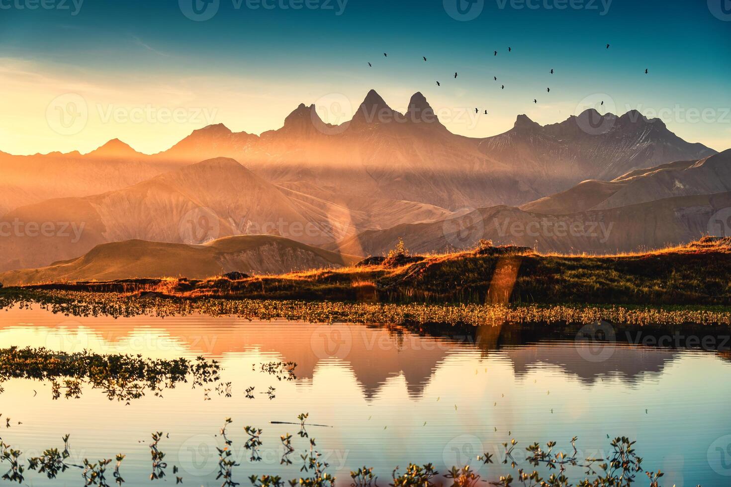 amanecer brilla terminado laca guichardo con pájaro volador en arve macizo y lago reflexión a agujas re arves, francés Alpes, saboya, Francia foto