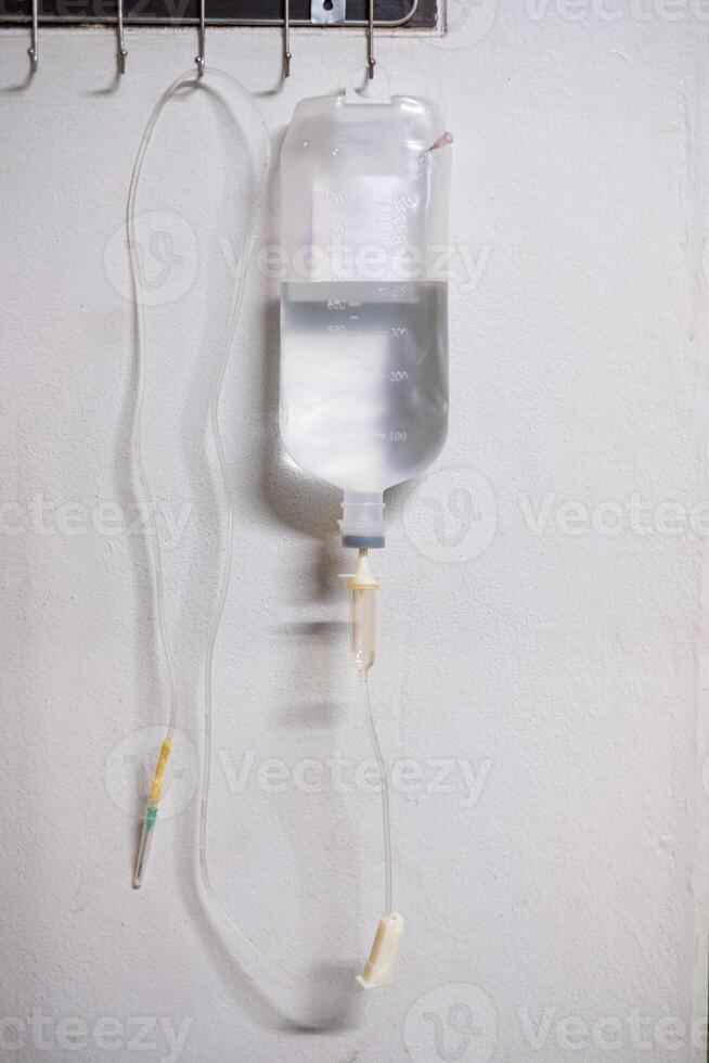 Saline solution iv bag with syringe line hanging on wall photo