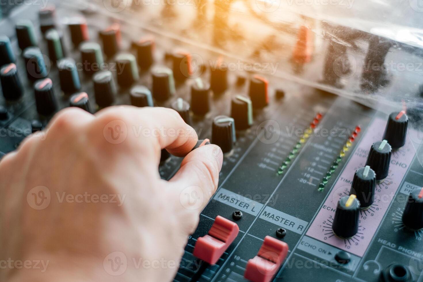 Close-up hand adjusting mixer sound on audio panel photo